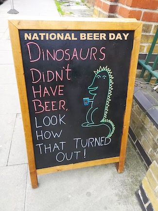 an outdoor sign at a bar about dinosaurs and beer